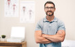 © peopleimages.com - Physiotherapist, portrait and office for sport, exercise or body care in wellness, help or gym at clinic. Male person, happiness and health as physiotherapy, fitness or rehab center with arms crossed