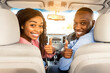© Prostock-studio - Test Drive, Great Ride, Good Car Concept. Portrait Of Excited African Amercan Couple Showing Thumbs Up Sign Gesture, Sitting On Front Seats In New Auto, Looking Vack At Camera Buying Vehicle In Store