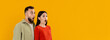 © Prostock-studio - A young couple showcases their surprise, with wide eyes and open mouths, looking at copy space, panorama