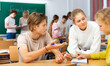 © JackF - Teenage schoolchilds working in groups at lesson in secondary school with teacher on background