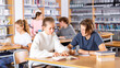 © JackF - Cute tween girl and intelligent boy studying together in school library, reading books