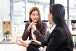© NAMPIX - Two young Asian business woman talking, consulting and discussing working with new startup project idea presentation in the office.