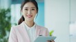 © Julia - Happy young Asian saleswoman looking at camera welcoming client. Smiling woman executive manager, secretary offering professional business services holding digital tablet standing in office.