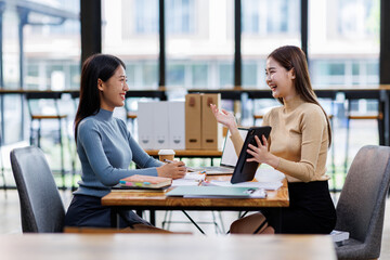 Wall Mural - Two asian female creative agency casual meeting discussion working with laptop, analyze planning and financial statistics and investment market at office.
