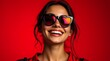 © Natsumae - Radiant smile, heart-shaped shades, vibrant red backdrop.  A captivating portrait of joy and style.