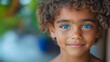 © CreativeIMGIdeas - A young child with blue eyes and brown hair is smiling. The child is wearing a blue shirt and has a blue eye shadow