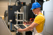 © juraj - Factory worker wearing safety glasses and hardhat operating industrial machinery using control panel in modern manufacturing plant