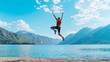 © Vasili - A dynamic shot of a person mid-jump in front of a scenic lake and mountain backdrop under a bright blue sky. Freedom and adventure concept.