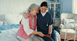 © peopleimages.com - Happy, senior woman and caregiver with tablet in bedroom for medical report, wellness news and healthcare. Elderly person, volunteer and hug for digital app, insurance update and information at house