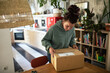 © Davor - Woman opening package in stylish home office
