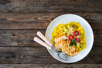 Wall Mural - Grilled sliced chicken breast with tagliatelle noodles on wooden table