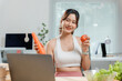 ©  NCST Studio - Asian nutritionist showing healthy food during an online video call consultation with her laptop at home