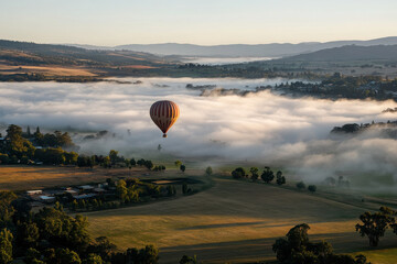 Poster - A hot air balloon floats over misty fields at sunrise, creating a serene landscape.