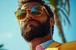 © Gatherina - Bearded businessman wearing yellow sunglasses and jacket under palm tree