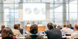 © antusher - Diverse group in conference room facing colorful screen design