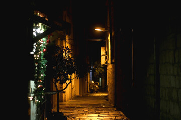 Wall Mural - Picturesque cobblestone alley in Split, Croatia at night, decorated with Cristmas decorations. Selective focus.