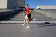 © Studio Marmellata - A man in a red shirt and a man in a black shirt jog side by side on a modern urban pathway with sleek architectural structures in the background under a clear blue sky