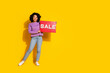 © deagreez - Full length photo of pretty young woman hold sale poster empty space isolated on yellow color background