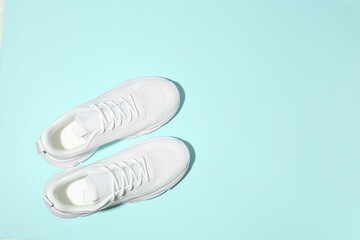 Wall Mural - Pair of stylish white sneakers on light blue background, top view. Space for text