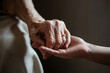 © Enrique Micaelo  - Mano de una anciana sujetando una mano de una persona joven. Generado con IA