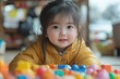 © Fotograf - A young child sits at a table surrounded by various toys and games