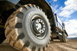 © romanets_v - Close-up of large off-road truck tire on dirt road with blue sky