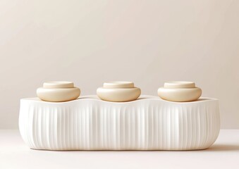 Leinwandbilder - Three beige cylindrical objects on a white ribbed platform against a neutral background.