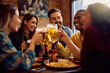 © Drazen - Group of happy friends drinking beer and toasting while gathering in pub.