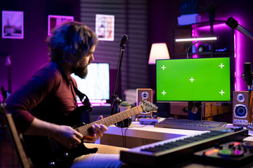 Poster - Artist playing acoustic guitar and following tutorials online on computer that shows greenscreen display. Music producer learning new instrument and accords to record tunes on daw software.