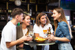 © JackF - Group of friends standing at table in bar, drinking beer and having conversation.