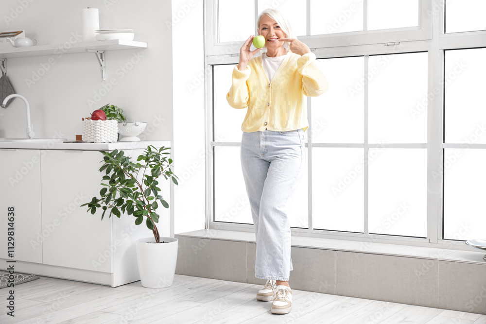 Mature woman pointing at apple in kitchen