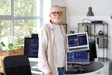 mature programmer with laptop in office