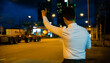 © sorapop - Asian businessman hailing taxi at night waving hand on city road. Beautiful woman smiles uses smartphone app to call cab after late work. Twilight urban transportation scene.
