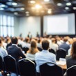 © Vadym - Large group of people sits in conference hall listening to presentation. Attendees dressed in business attire. Blurred image conveys busy corporate seminar training session. Many people present
