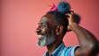 Joyous Expression of an Older Man Adorned With Colorful Pom-Poms Against a Vibrant Pink Background