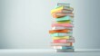 © MAY - Colorful Stacks A stack of brightly colored books arranged haphazardly, creating a vibrant and playful composition against a simple background.