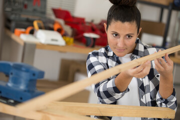 portrait of happy professional female carpenter looking at wood