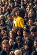 © Derek Brumby - Diverse Audience with One Woman in Bright Yellow Jacket Standing Out in Crowd