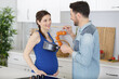 © auremar - pregnant couple cooking together in the kitchen