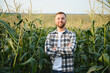 © Serhii - Yong handsome agronomist in the corn field and examining crops before harvesting. Agribusiness concept. agricultural engineer standing in a corn field