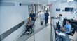 © Gorodenkoff - Male and Female Medical Professionals Navigate a Hospital Corridor and Registration Area, Having Healthcare Conversations. Male Nurse Assists a Patient in a Wheelchair