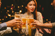 © Witoon - A group of fun friends gather outdoors, raising their glasses in celebration. They smile and laugh, enjoy beers and have lively conversations, showing friendship, fun.