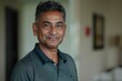 © Markus Schröder - Portrait of a satisfied indian man in his 40s wearing a breathable golf polo isolated in bare monochromatic room