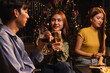 © SOMKID - Group of friends clinking wine glasses in celebration at night, Festival celebration, Happy Asian group friends and dinner party in the night, Friendship and celebration new year concept.