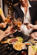 © SOMKID - Group of friends clinking wine glasses in celebration at night, Festival celebration, Happy Asian group friends and dinner party in the night, Friendship and celebration new year concept.