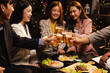 © SOMKID - Group of friends clinking beer glasses in celebration at night, Holiday, Festival celebration, Happy Asian group of friends and dinner party in the night, Friendship and celebration new year concept.