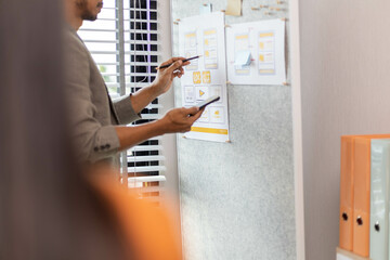 A man and a woman are looking at a table with a lot of cards and a laptop. The cards are about UX design and the laptop is open. Scene is focused and serious