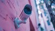 © AI_Nusantara - Security camera mounted on pink wall.