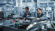 © Gorodenkoff - Indian And Caucasian Male Workers Taking Apart Laptops To Recycle For Production Of High Tech Devices At Automated Electronics Factory With Robotic Arms. Colleagues Sorting Displays, Keyboards.