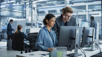 Fototapete - Portrait of a Young Male Assembly Line Worker and Hispanic Female Engineer Collaborating on a Project, Using Computer and Talking in a Factory with Robotic Arms Producing Devices for Tech Industries.